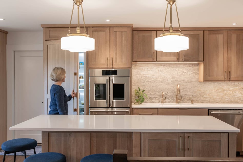Homeowner opening a hidden pantry in a custom kitchen remodel by HC Remodel & Design in Council Bluffs, NE.-optimized