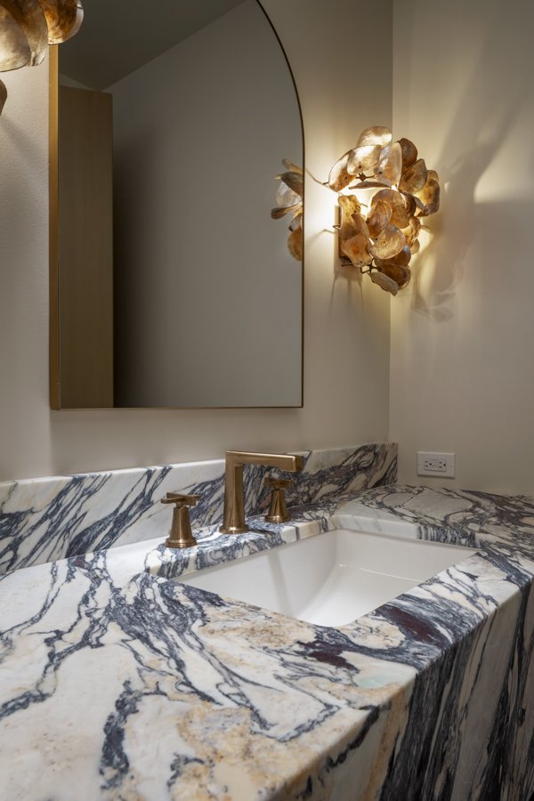 Luxury bathroom remodel in Omaha, NE by HC Remodel & Design with a custom marble countertop, integrated sink, and arched mirror.-optimized