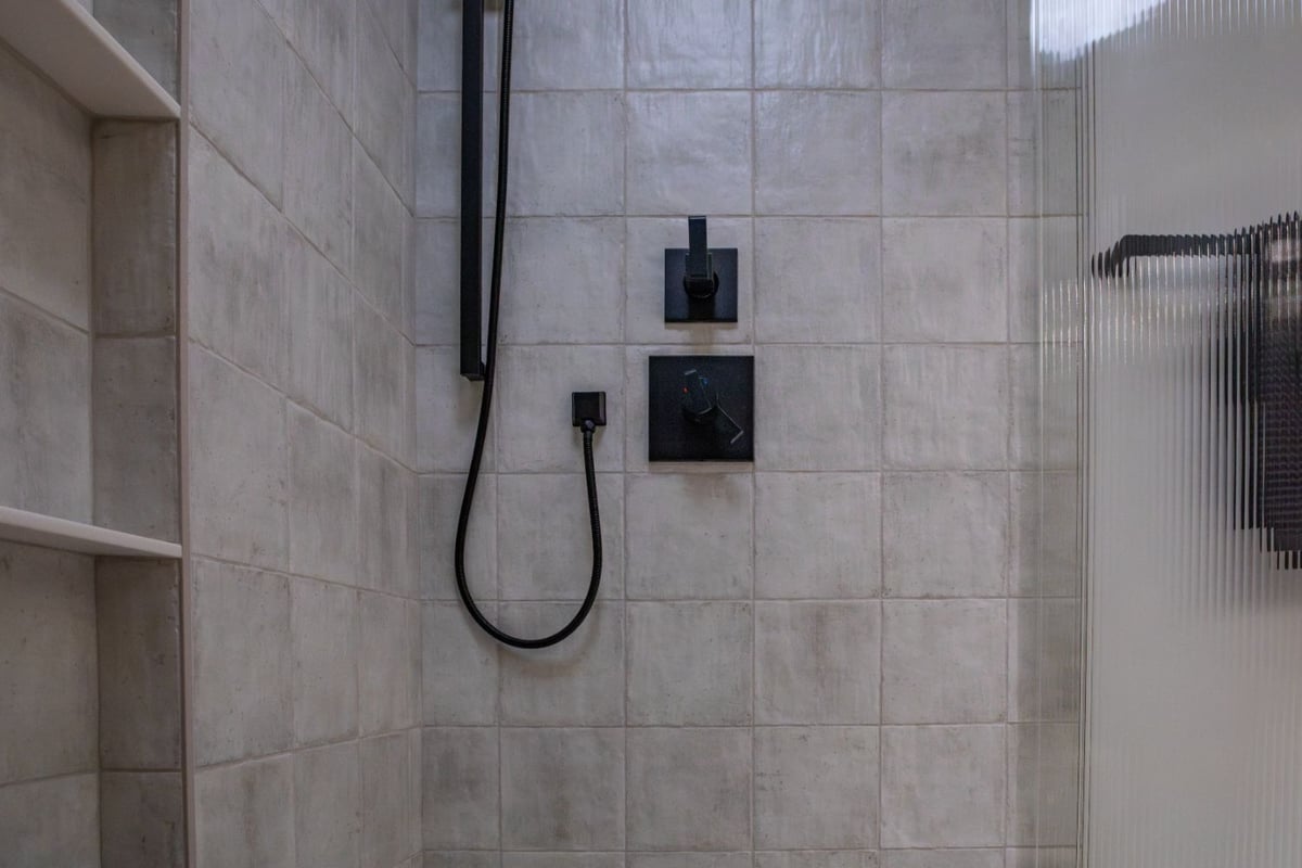 Modern Omaha, NE bathroom by HC Remodel & Design showcasing a custom tiled shower with sleek black hardware and neutral tile.-optimized