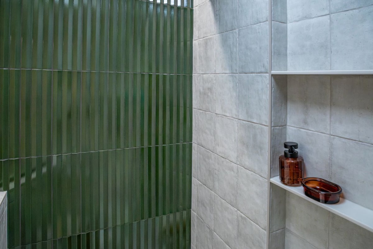 Modern shower with green vertical tile walls and gray tile surround by HC Remodel & Design in Omaha, NE.-optimized