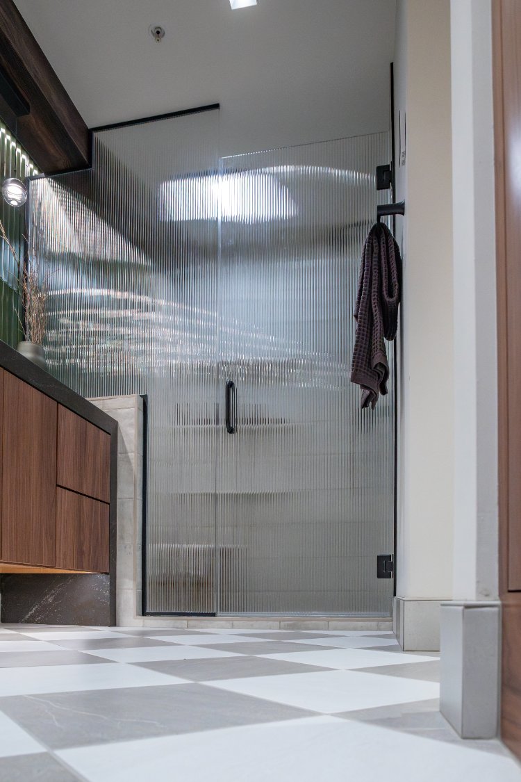 Stylish bathroom by HC Remodel & Design in Omaha, NE showcasing a ribbed glass shower and green tile feature wall.-optimized