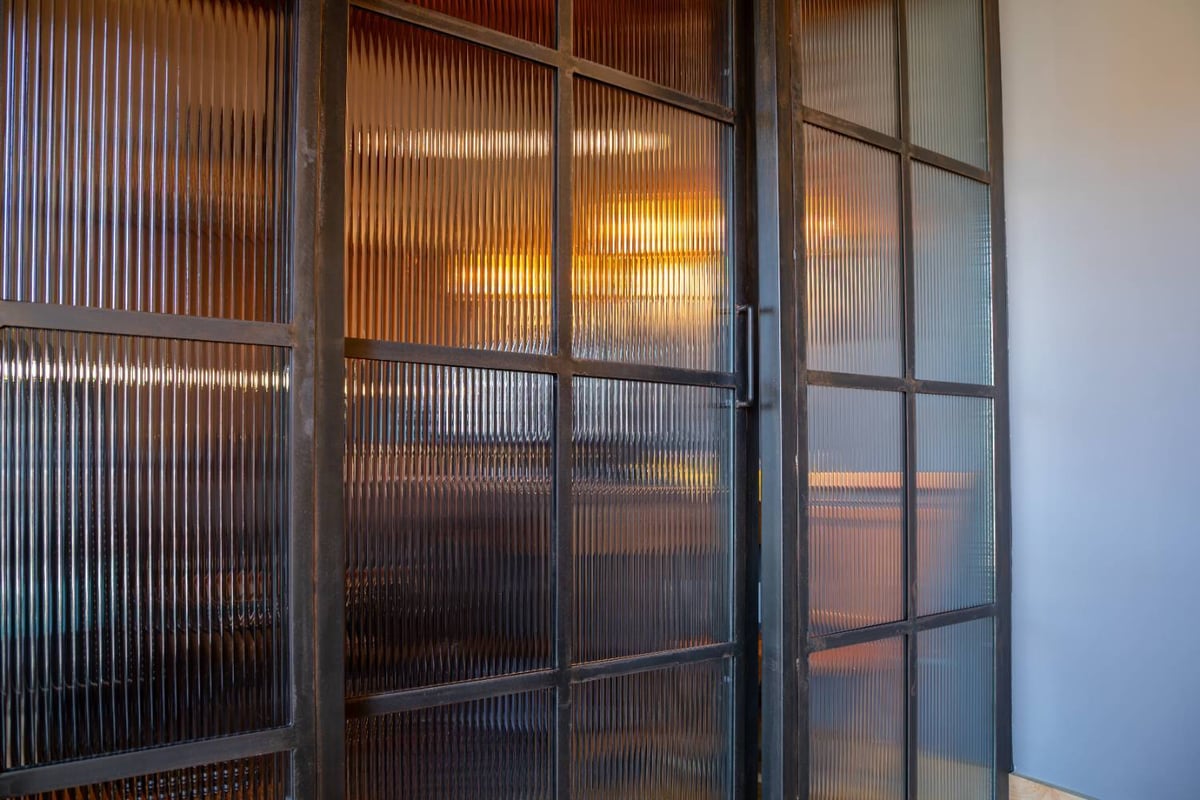 Angled view of a steel-framed fluted glass office partition by HC Remodel & Design in Omaha, NE.-optimized