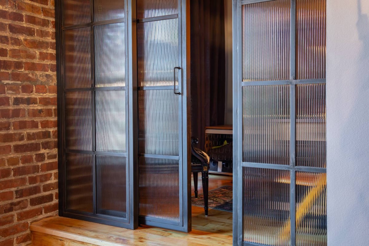 Close-up of a custom steel and fluted glass sliding office door by HC Remodel & Design in Omaha, NE.-optimized