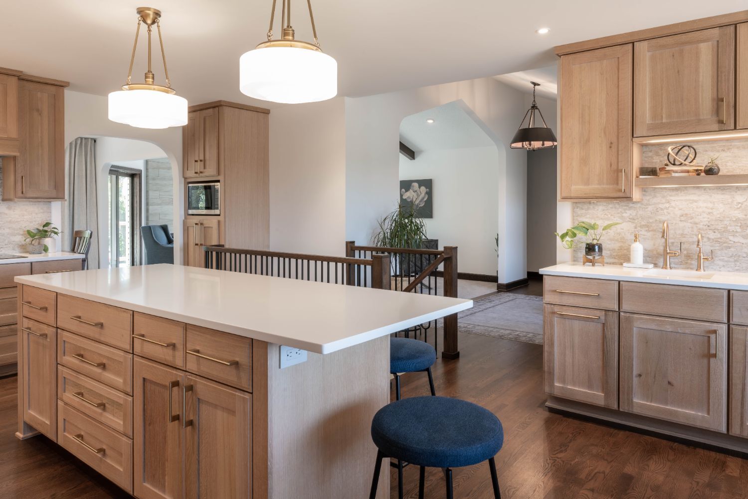 Bright kitchen remodel by HC Remodel & Design featuring a large white island, warm wood cabinetry, and quartz countertops