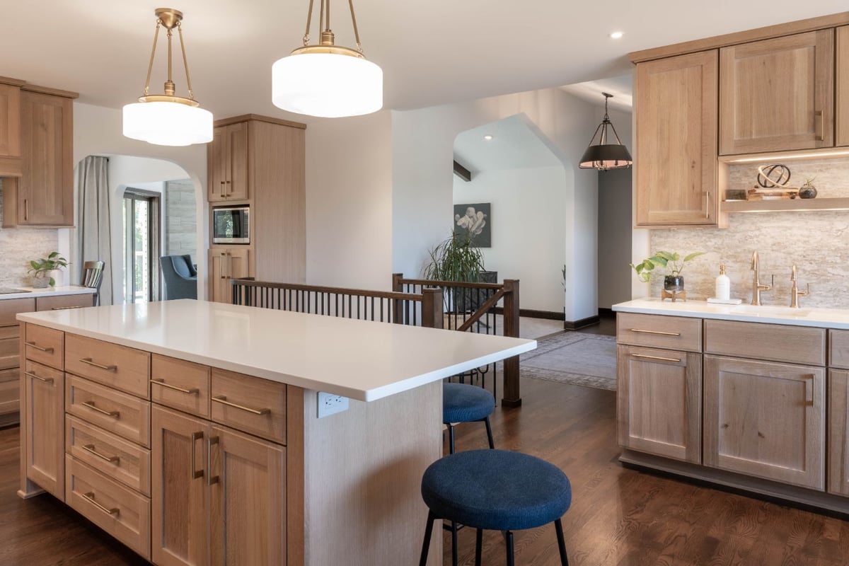 Bright kitchen remodel by HC Remodel & Design featuring a large white island, warm wood cabinetry, and quartz countertops in Cou-optimized