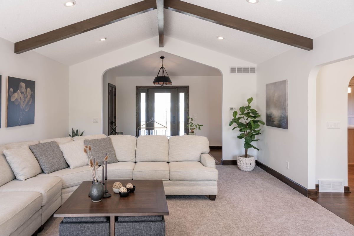 Open living room renovation in Omaha, NE by HC Remodel & Design with wood beams, neutral furnishings, and modern styling.-optimized