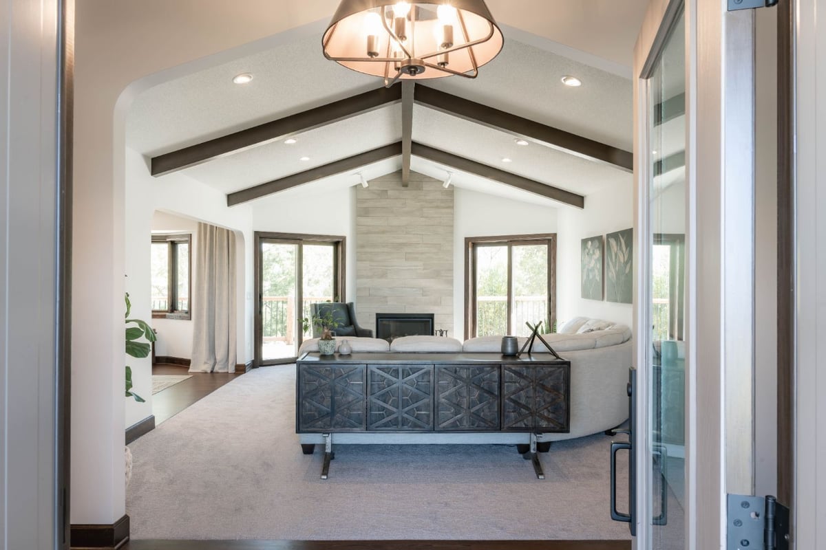 Open-concept living room by HC Remodel & Design in Omaha, NE with vaulted ceilings, large windows, and contemporary finishes.-optimized
