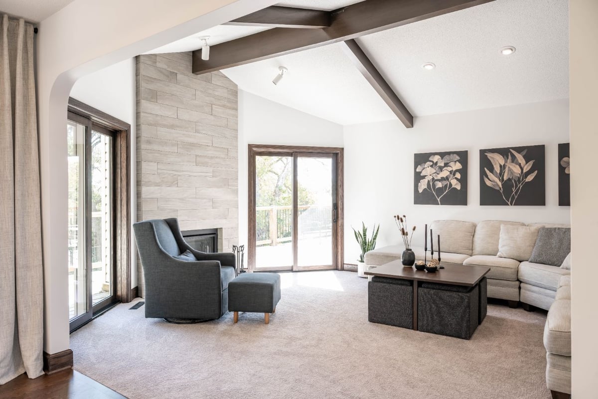 Open-concept living room remodel by HC Remodel & Design in Omaha, NE featuring a tiled fireplace, vaulted ceiling, and large win-optimized
