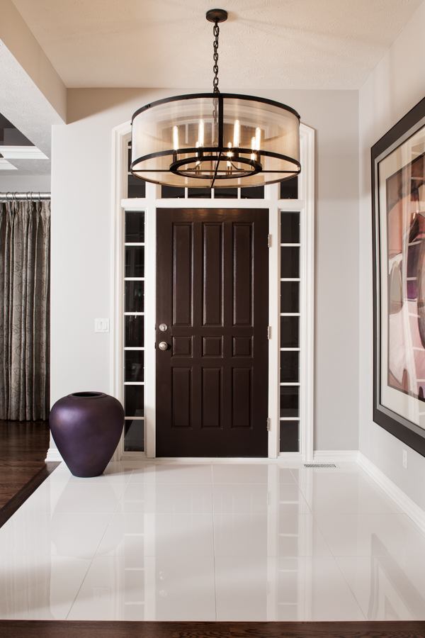 Modern entryway remodel by HC Remodel & Design in Omaha, NE featuring glossy tile flooring, a statement chandelier, and dark woo-optimized