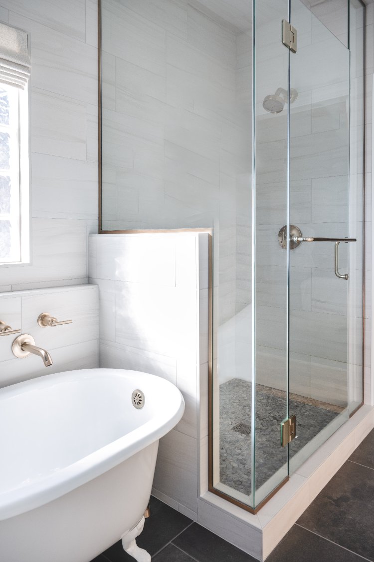 Brushed brass wall-mounted tub filler above a freestanding soaking tub in a primary bathroom remodel by HC Remodel & Design in P-optimized