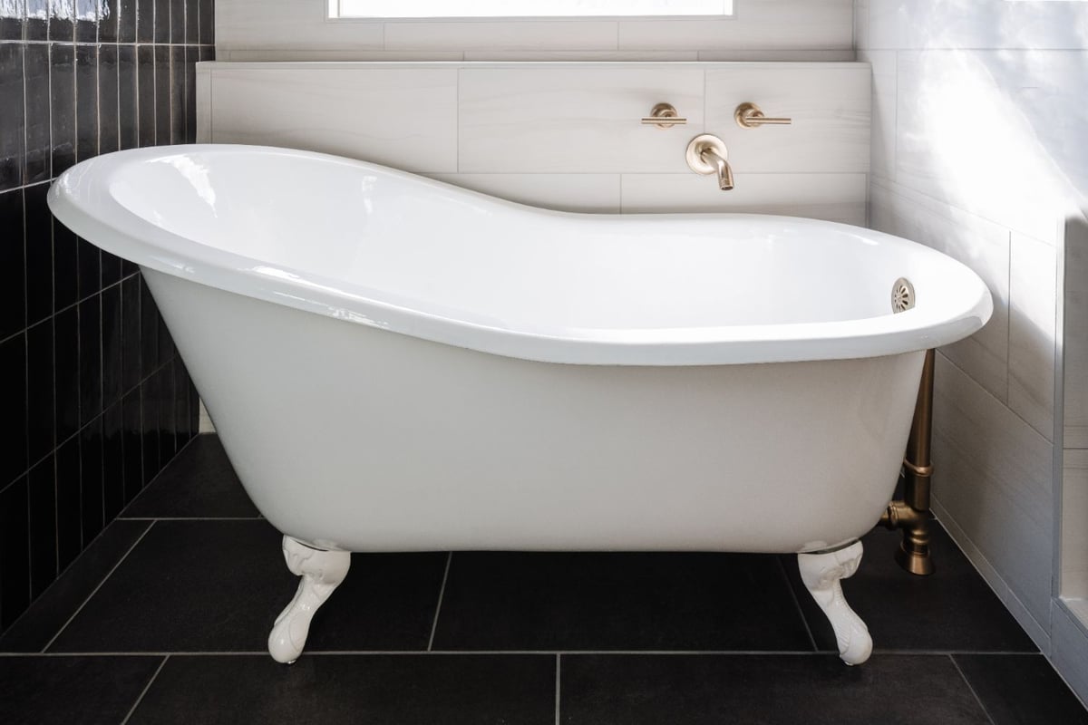 Freestanding soaking tub with brushed brass tub filler in a primary bathroom remodel by HC Remodel & Design in Papillion, NE.