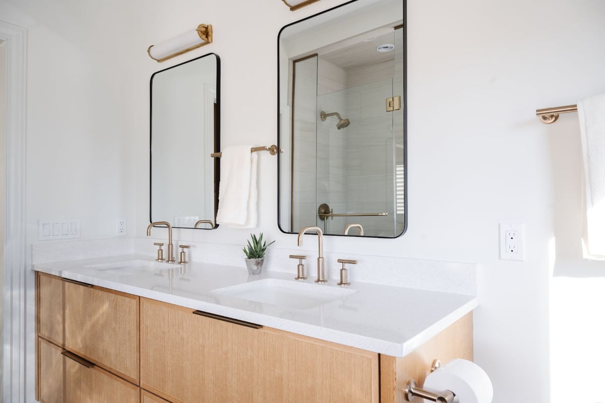 Modern double vanity with white quartz countertops and brushed brass fixtures in a primary bathroom remodel by HC Remodel & Desi-optimized