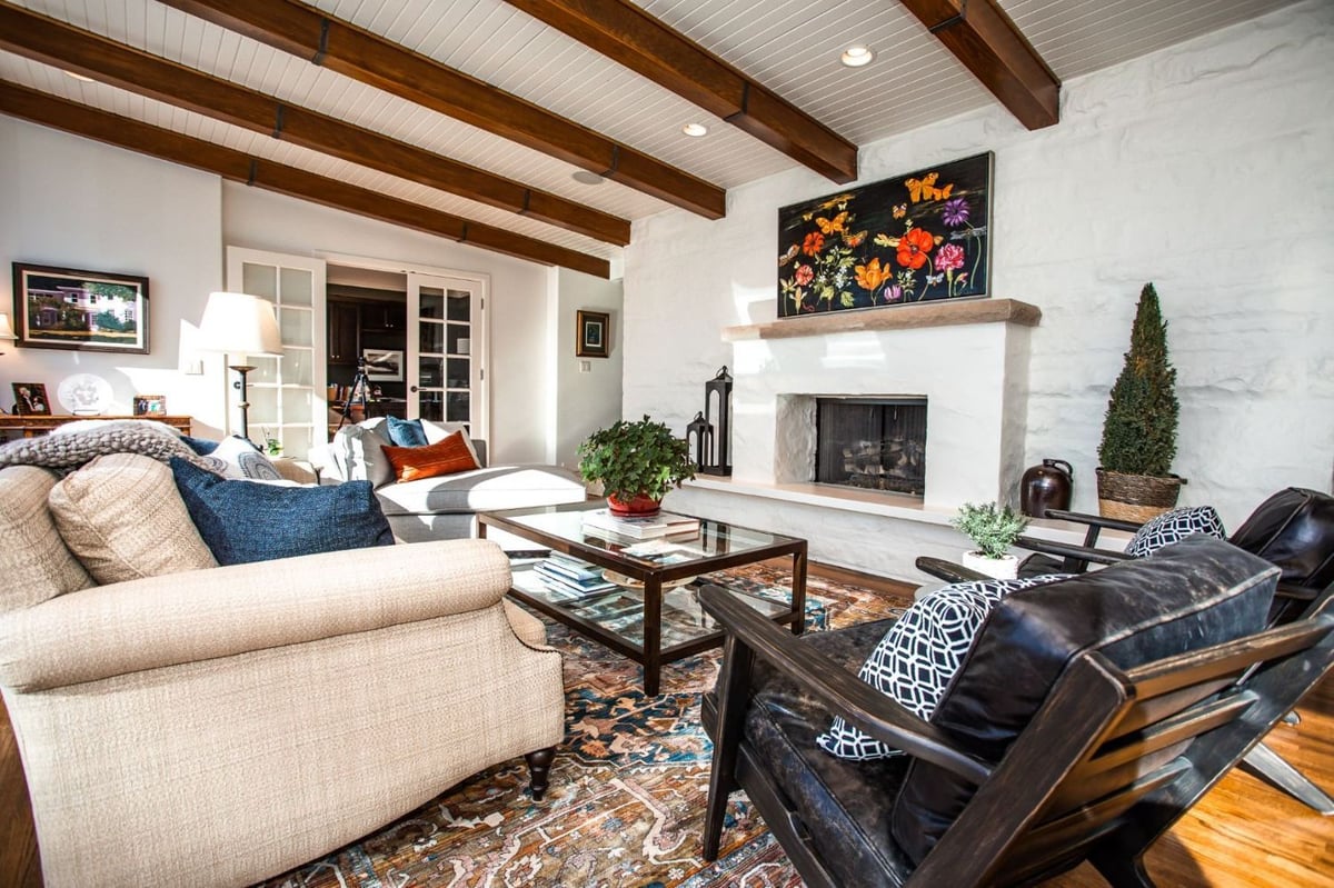 First floor living room remodel by HC Remodel & Design in Omaha, NE with a white fireplace surround, hardwood floors, and vaulte-optimized
