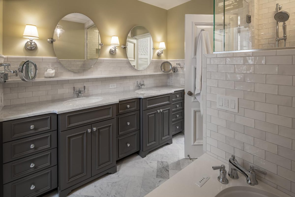 Double-sink vanity in a primary bath remodel by HC Remodel & Design in Omaha, NE with dark cabinetry, marble counters, and subwa-optimized