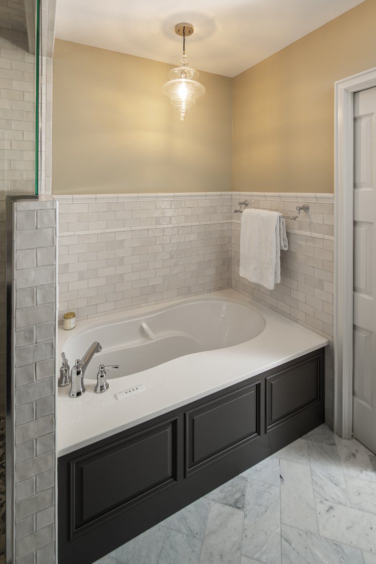 Luxury soaking tub in a primary bath remodel by HC Remodel & Design in Omaha, NE with subway tile wainscoting and elegant finish-optimized