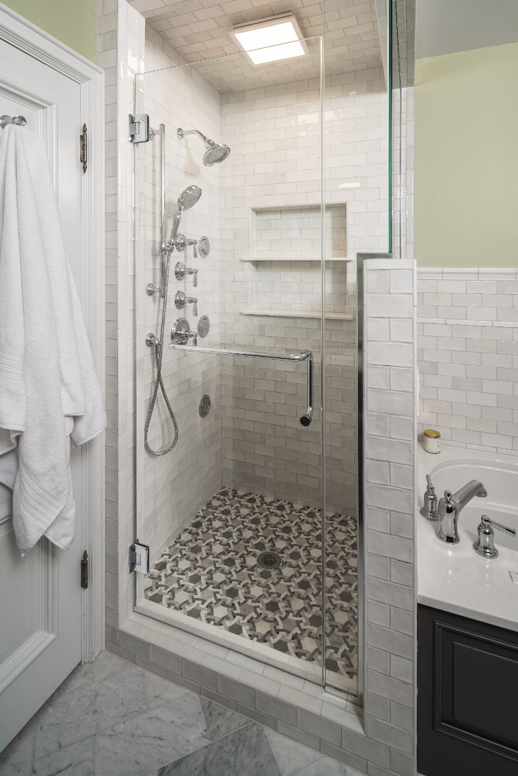 Walk-in shower in a primary bath remodel by HC Remodel & Design in Omaha, NE with patterned tile flooring and recessed storage n-optimized