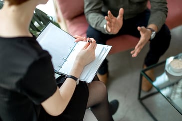 Image of a person taking notes while another person is talking to them