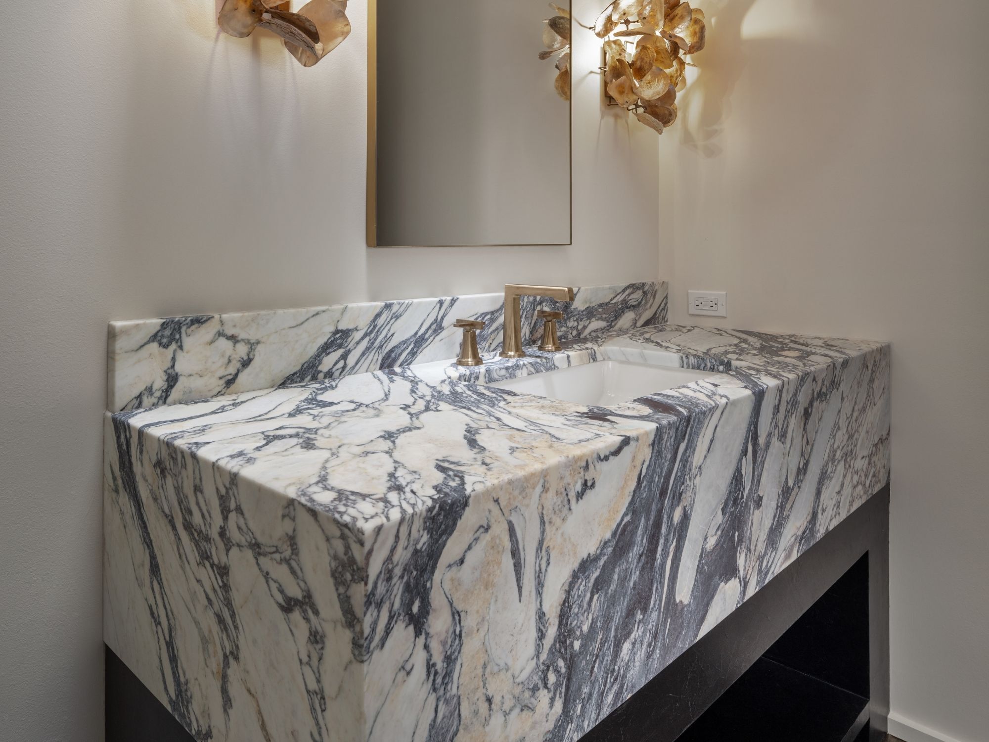 Marble bathroom vanity with bold veining, integrated sink, and brass faucet in Omaha & Council Bluffs.