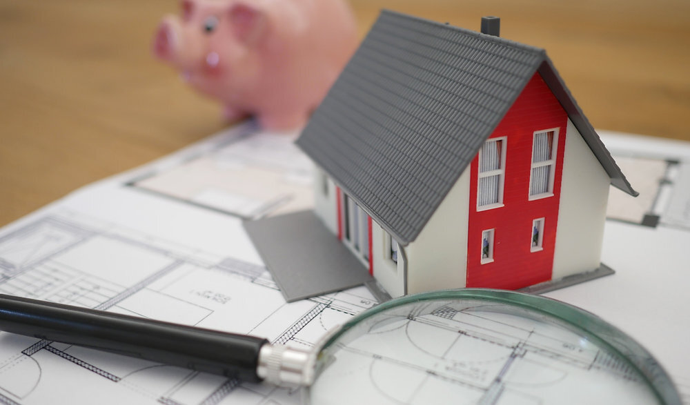 Stock image of a little house sitting on top of blueprints